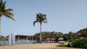 Une plage bordée de palmiers, avec des parasols et des chaises longues.
