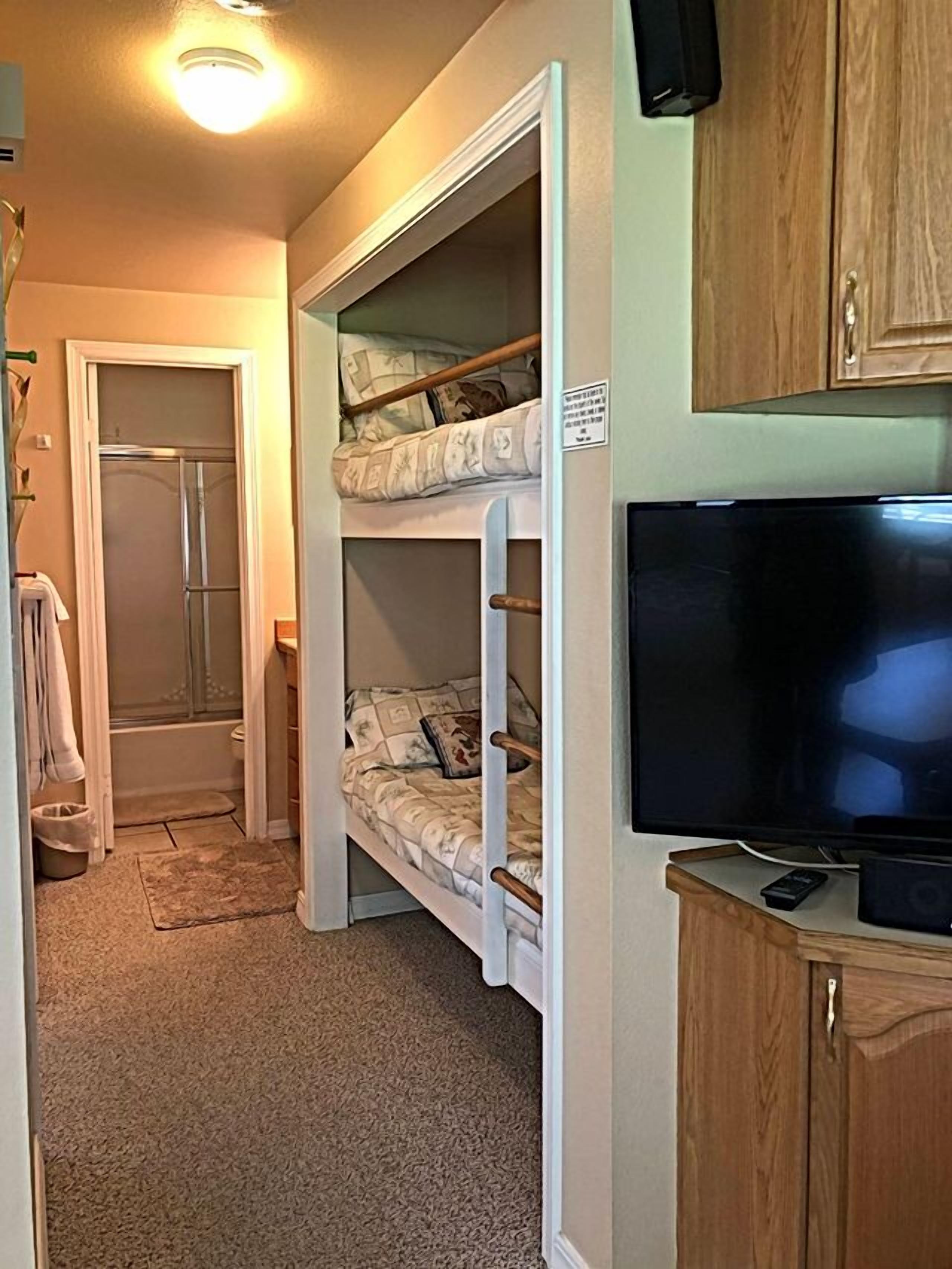 A compact room with bunk beds, a television, and a small cabinet.