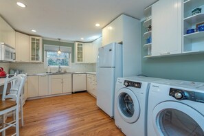 A compact kitchen with white cabinetry, a microwave, a sink, and a washing machine.