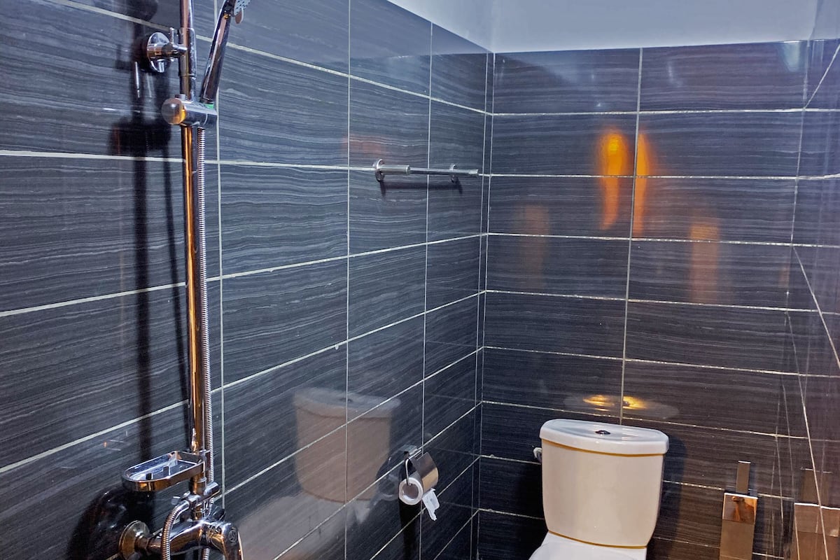 Un baño moderno con ducha, inodoro y barra para toallas.