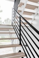 Una escalera moderna con barandillas negras y peldaños de madera.