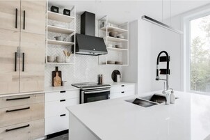 Una cocina moderna con armarios blancos, una campana extractora negra y un amplio ventanal que proporciona luz natural.