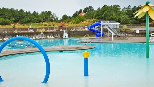 A swimming pool with a slide, lounge chairs, and a lifeguard stand. - Pet-Friendly OBX Retreat - 3BR/2BA -  Private Beach Parking MP6 Kill Devil Hills (Kill Devil Hills)