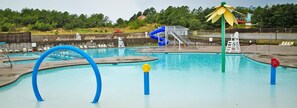 A swimming pool with a slide, lounge chairs, and a lifeguard stand.
