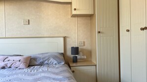 Een slaapkamer met een bed, nachtkastje en kledingkast.