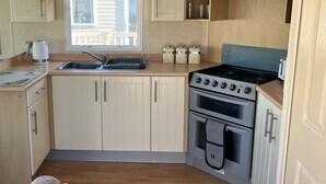 Een kleine keuken met een gootsteen, fornuis en kastjes.