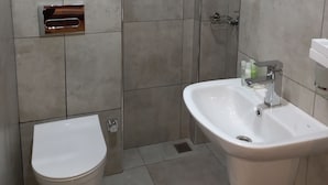 A modern bathroom with a toilet, sink, and shower. - Acacus Hotel (Kigali)