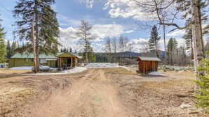 A rural landscape with a dirt road, wooden cabins, and a forested area. - Hike, Bike & Boat: Cabin w/ Dock on Seeley Lake! (Seeley Lake)
