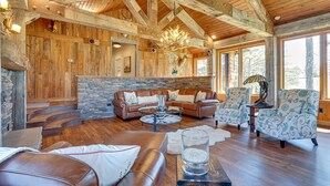 A rustic interior with a stone fireplace, leather sofas, and a chandelier. - Spacious Alabama Retreat - Deck, Grill & Fire Pit! (Crane Hill)