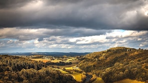 A rural landscape with rolling hills, a river, and scattered buildings.