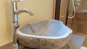A stone sink with a modern faucet in a bathroom.