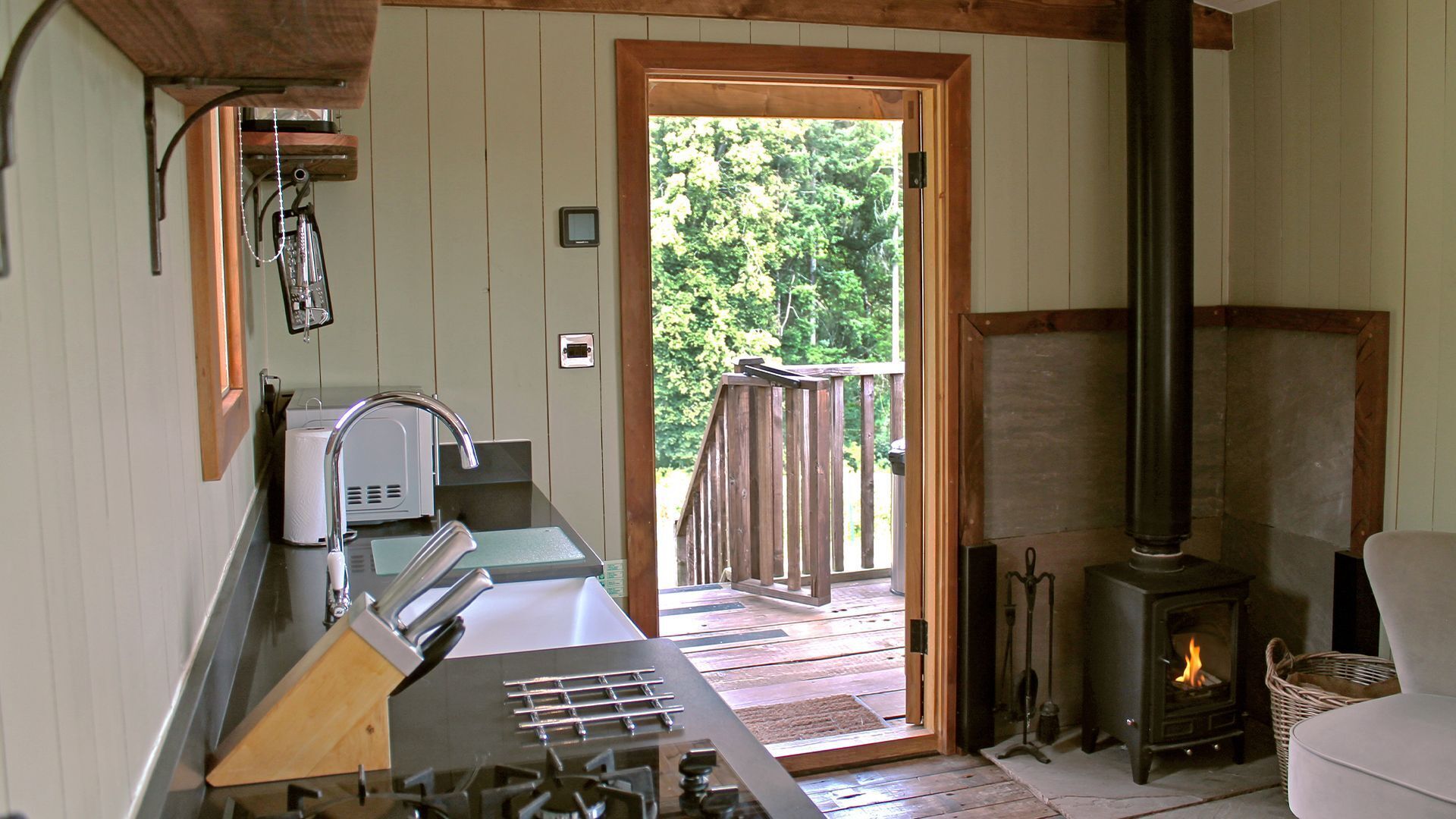 L’intérieur d’un chalet rustique comprend un coin cuisine, une cheminée et une terrasse en bois.