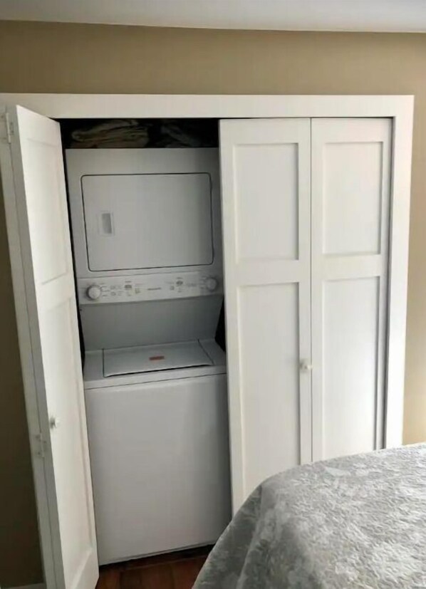 Un lavadero pequeño y funcional con lavadora, secadora, un estante y una puerta.
