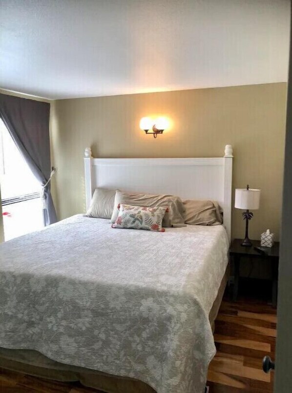 Une chambre à coucher comprenant un lit, une table de chevet, une lampe et un luminaire fixé au mur.