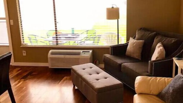 A living room with a large window, a sofa, an ottoman, and a lamp. - #139 Condo near large pool & shuttle to Gorge Amp-book separately (Quincy)