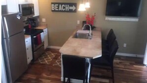 A compact kitchen with a microwave, refrigerator, and a sink. There's a sign on the wall that reads "BEACH" with an arrow pointing right. - #139 Condo near large pool & shuttle to Gorge Amp-book separately (Quincy)