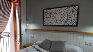 A bedroom with a bed, two pillows, a decorative wall panel, and a wooden headboard. - Raoret House in the Old Town (Villajoyosa)