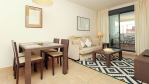 Uma sala de estar moderna com uma mesa de jantar, cadeiras, um sofá e uma mesa de centro.