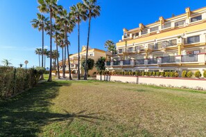 Un hôtel à plusieurs étages doté de balcons, d’une pelouse bien entretenue et de palmiers.