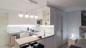 A modern kitchen with a central island, bar stools, a microwave, and a dishwasher.