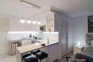 A modern kitchen with a central island, bar stools, a microwave, and a dishwasher. - Deluxe studio with huge terrace - Romana Playa beachfront (Marbella)