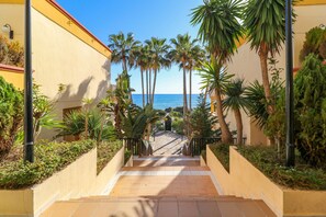 A pathway leading to a beach with palm trees and a clear view of the sea. - Deluxe studio with huge terrace - Romana Playa beachfront (Marbella)