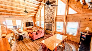 A log cabin interior with a fireplace, wooden walls, a dining area, and a sofa. - Luxury Log Cabin • Paradise in the Lakes Region (Naples)