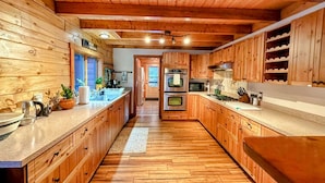 A wooden interior with a kitchen featuring wooden cabinets, a countertop, a sink, and a stove. - Luxury Log Cabin • Paradise in the Lakes Region (Naples)