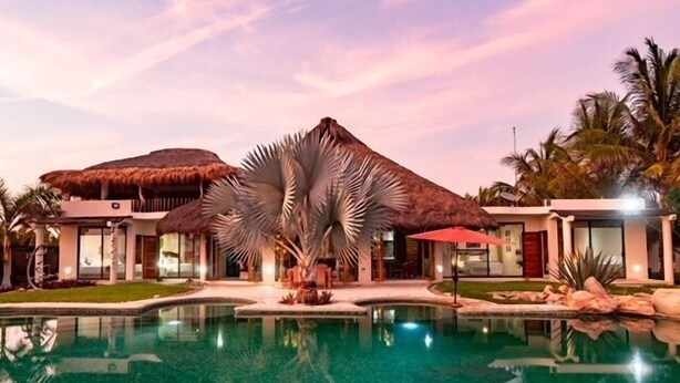 A resort with a pool, thatched-roof structures, and palm trees. - Villa De Las Rocas- Luxury Rental, Puerto Escondido, Villa de las Rocas - Luxury Rental, Puerto Esco (Puerto Escondido)