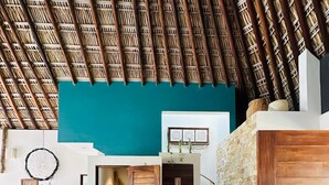 A spacious interior with a high thatched ceiling, a staircase, and a large blue patterned rug. - Villa De Las Rocas- Luxury Rental, Puerto Escondido, Villa de las Rocas - Luxury Rental, Puerto Esco (Puerto Escondido)