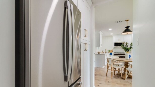 A modern kitchen with stainless steel appliances, white cabinetry, and a wooden dining table with chairs. - KING Bed/Central Location/Fast wi-fi/5star listing (Lafayette)