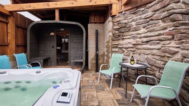 A spa area with a hot tub, chairs, and a stone wall. - Marika 1 by Interhome (Cerny Dul)