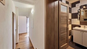 A modern hallway with wooden flooring, a wooden door, and a bathroom with a mirror and sink. - Marika 1 by Interhome (Cerny Dul)