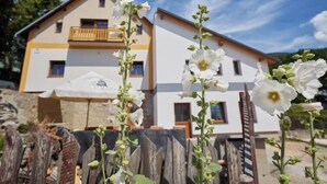 Un bâtiment à deux étages, doté d’un balcon à l’étage supérieur, et entouré de fleurs blanches.