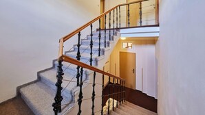 Un escalier avec une rampe en bois et des balustres noires menant à un palier doté d’une porte.