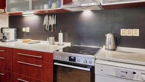 Une cuisine moderne avec des meubles en bois, une cuisinière à gaz, un four et une machine à café.