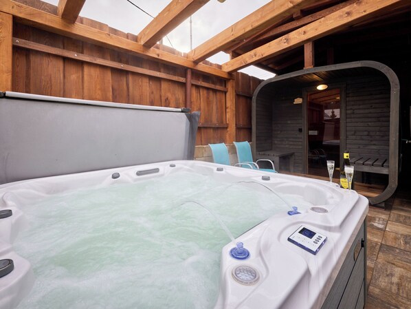 A hot tub with a control panel, two chairs, and a bottle of wine.