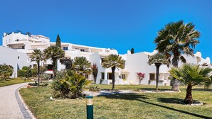 A white building with multiple balconies and palm trees in the foreground. - Apartment Delphine with pool (Porches)