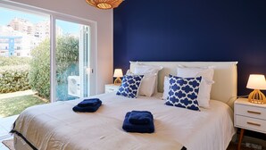 A bedroom with a large bed, two bedside tables, and a view of the outdoors. - Apartment Delphine with pool (Porches)