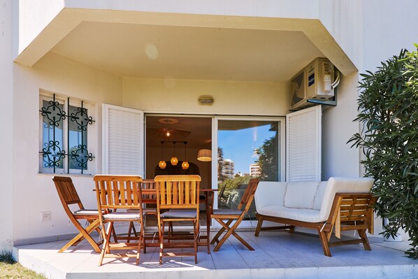 Eine Terrasse im Freien mit Holzmöbeln, darunter ein Tisch, Stühle und eine Couch.