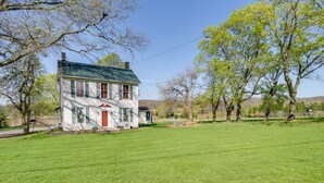 A two-story house with a green roof, surrounded by a well-maintained lawn and trees. - Rustic Wellsville Home - 5 Mi to Roundtop Mountain (Wellsville)