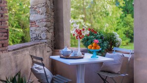 Eine Terrasse mit einem weißen Tisch, gedeckt für Tee, umgeben von Backsteinmauern und Grünpflanzen.