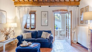 Ein gemütliches Wohnzimmer mit einem blauen Sofa, einer Holzbalkendecke und Blick ins Freie.