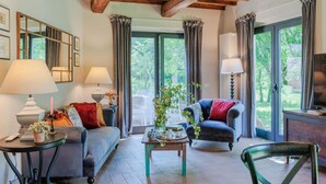 A cozy living room with a wooden ceiling, a sofa, a chair, a coffee table, and a TV.