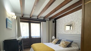 Una camera da letto con un letto, travi in legno, una piccola finestra e una porta.