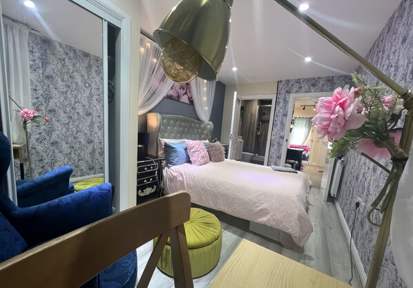 A modern bedroom with a bed, a chair, and a vanity.