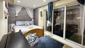 Een slaapkamer met een bed, een houten hoofdbord, een nachtkastje, een raam met gordijnen en uitzicht op buiten.