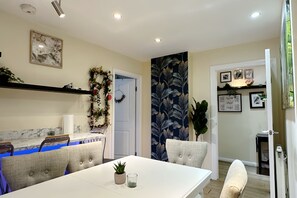 A dining area with a white table, blue chairs, and a decorative wall with a floral pattern.