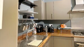 Een keuken met een spoelbak, fornuis en kastjes.