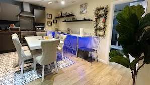 Een moderne keuken met een eethoek, met een witte tafel, stoelen en een bar met blauwe verlichting.